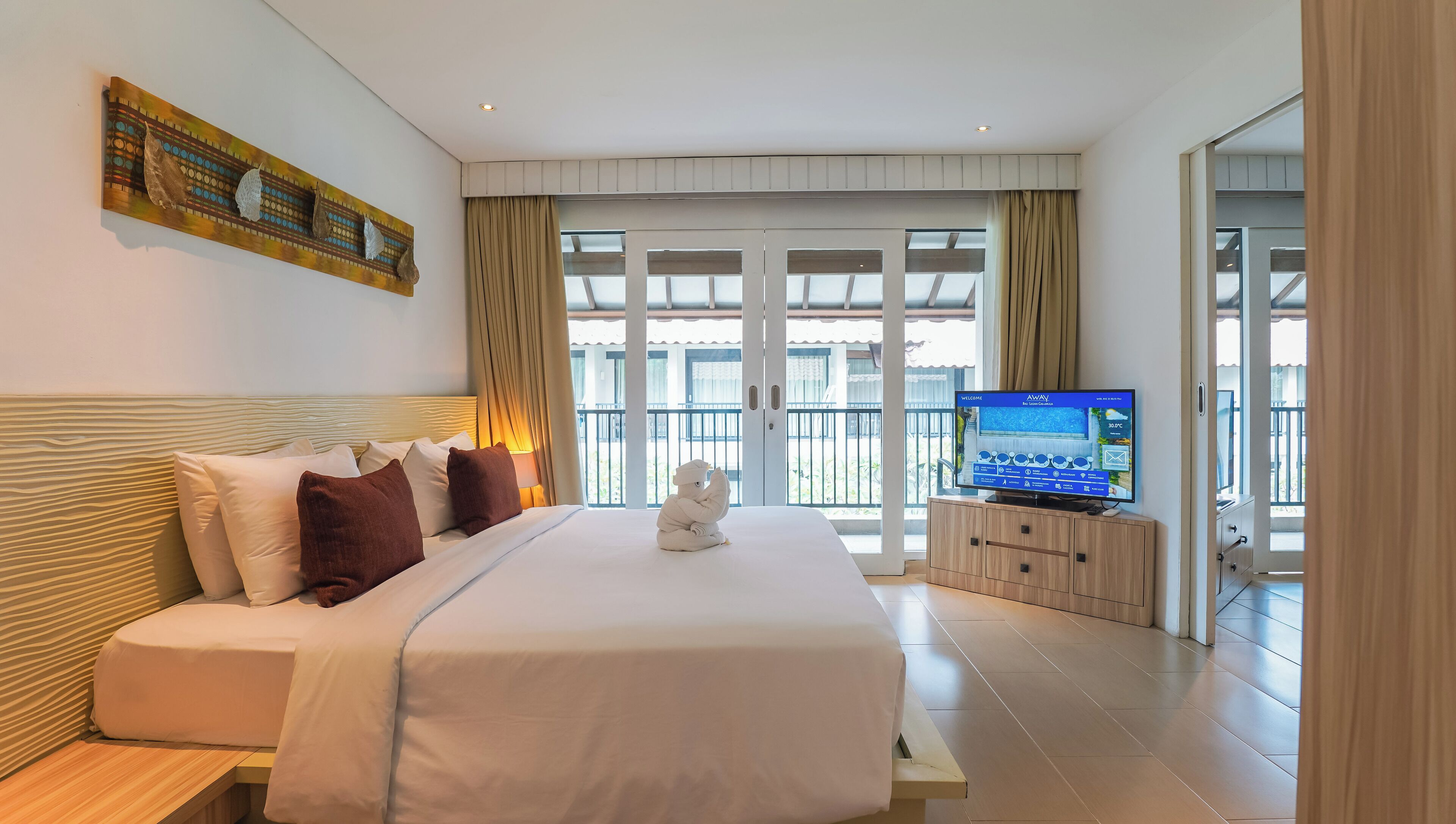 A modern hotel room with a large bed, a television, and a view of the outdoors.