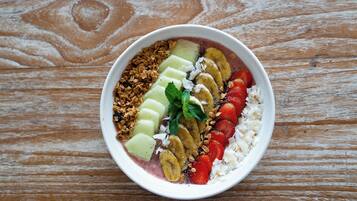 Eine Schüssel mit Obst und Granola auf einer Holztischplatte.