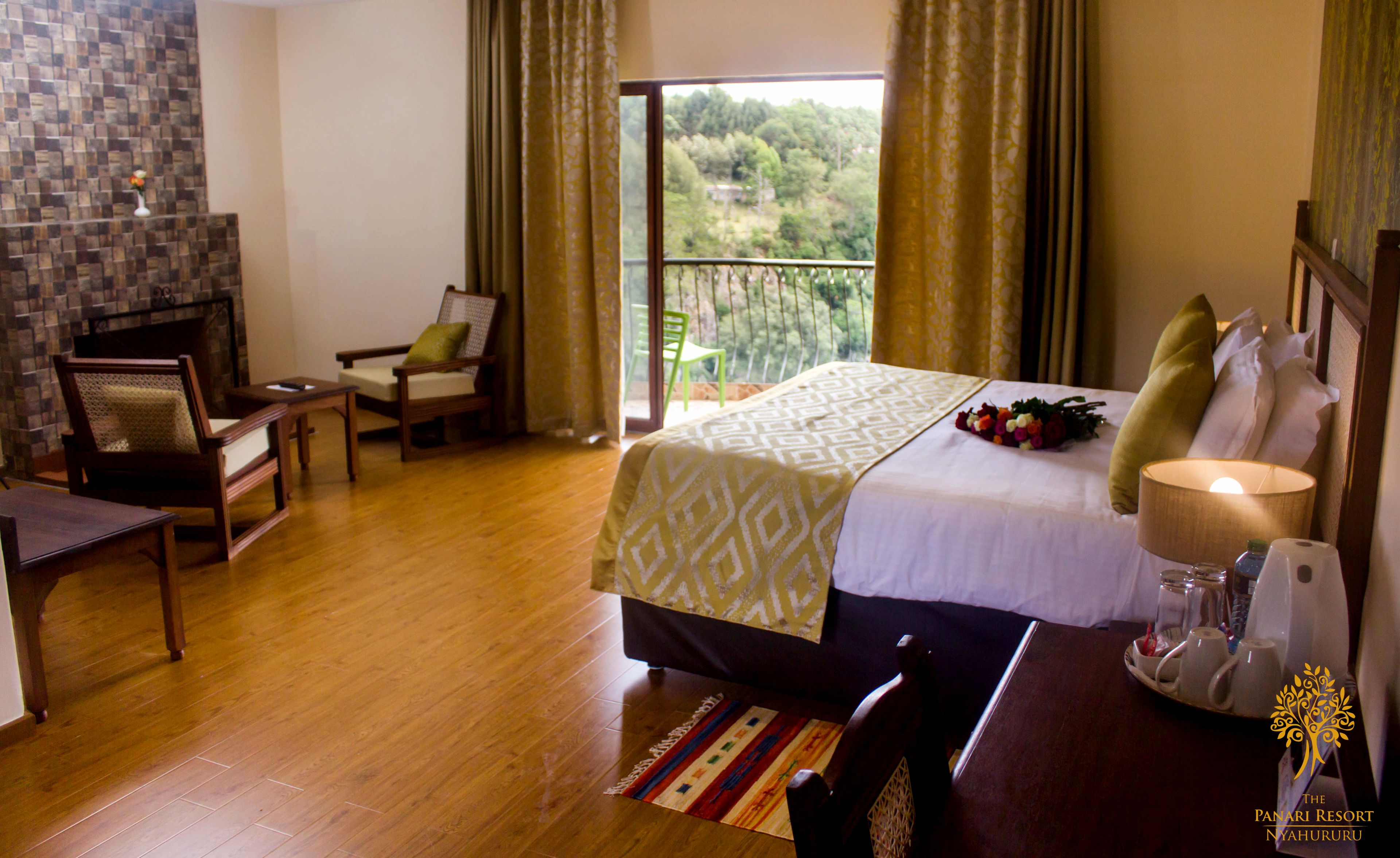 A hotel room with a bed, a chair, a small table, and a view of the outdoors.