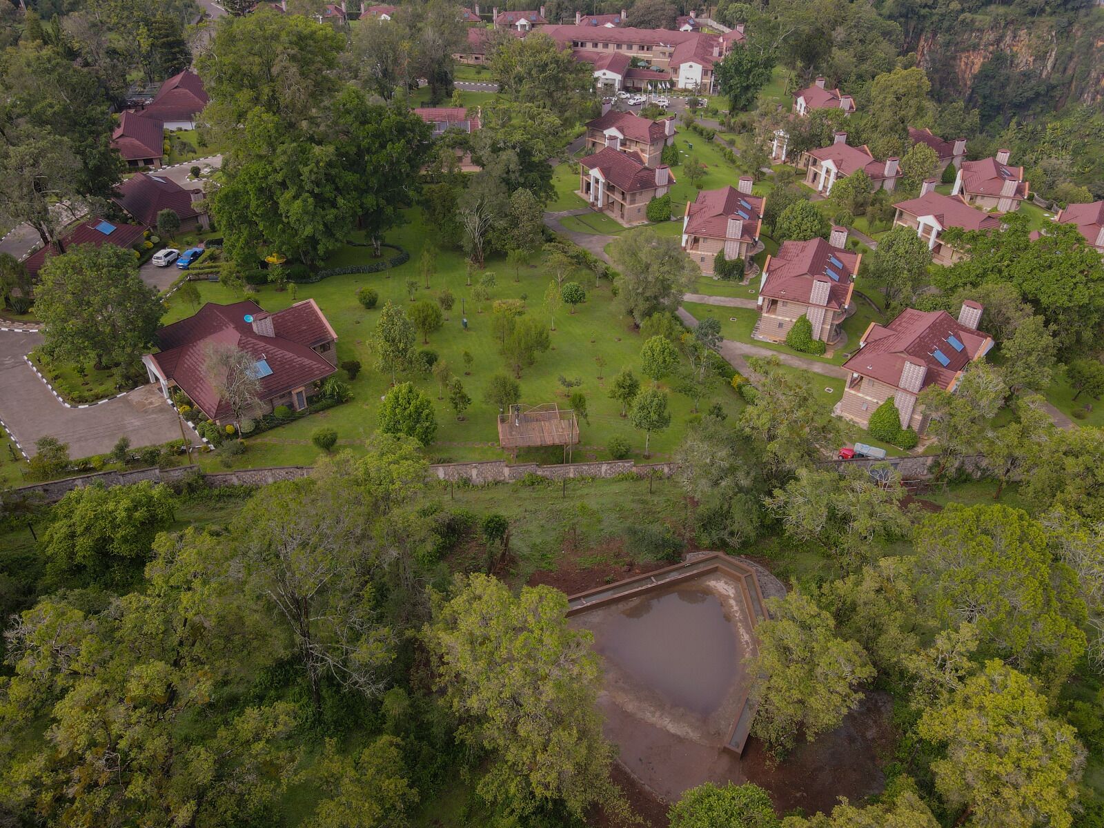 An aerial view of a residential area with houses, green lawns, and a small pond.