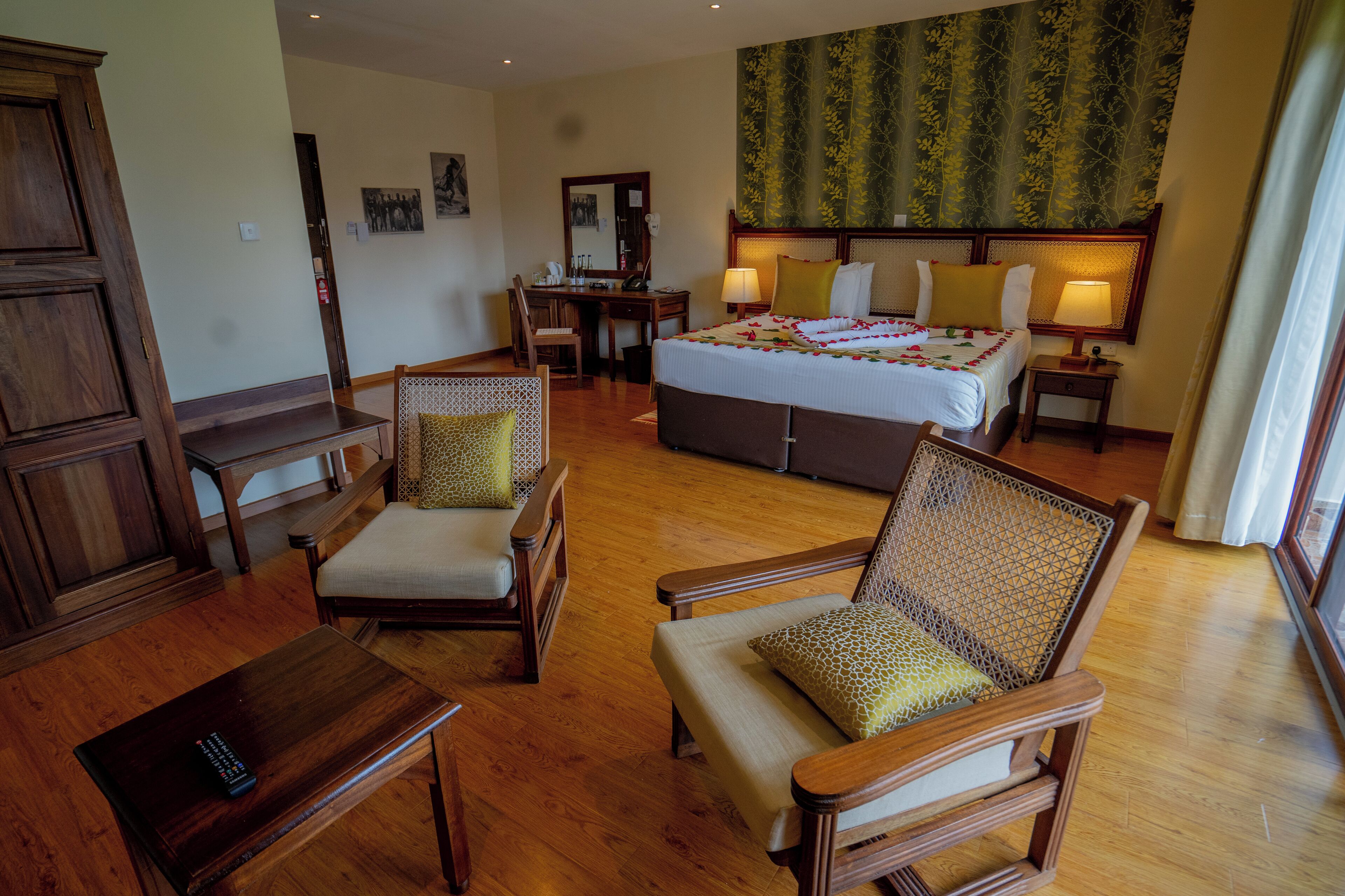 A hotel room with a bed, two chairs, a desk, and a wardrobe.