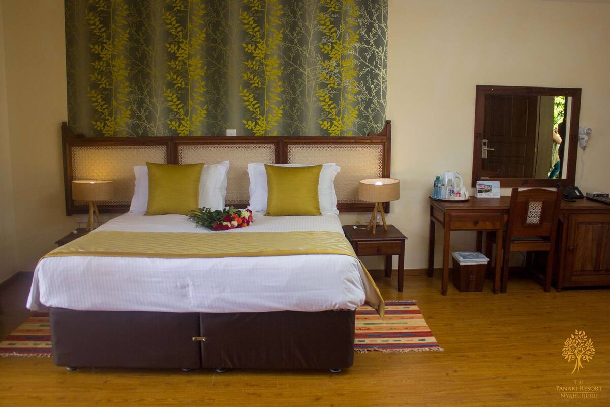 A hotel room with a large bed, two bedside tables, a desk, and a mirror.