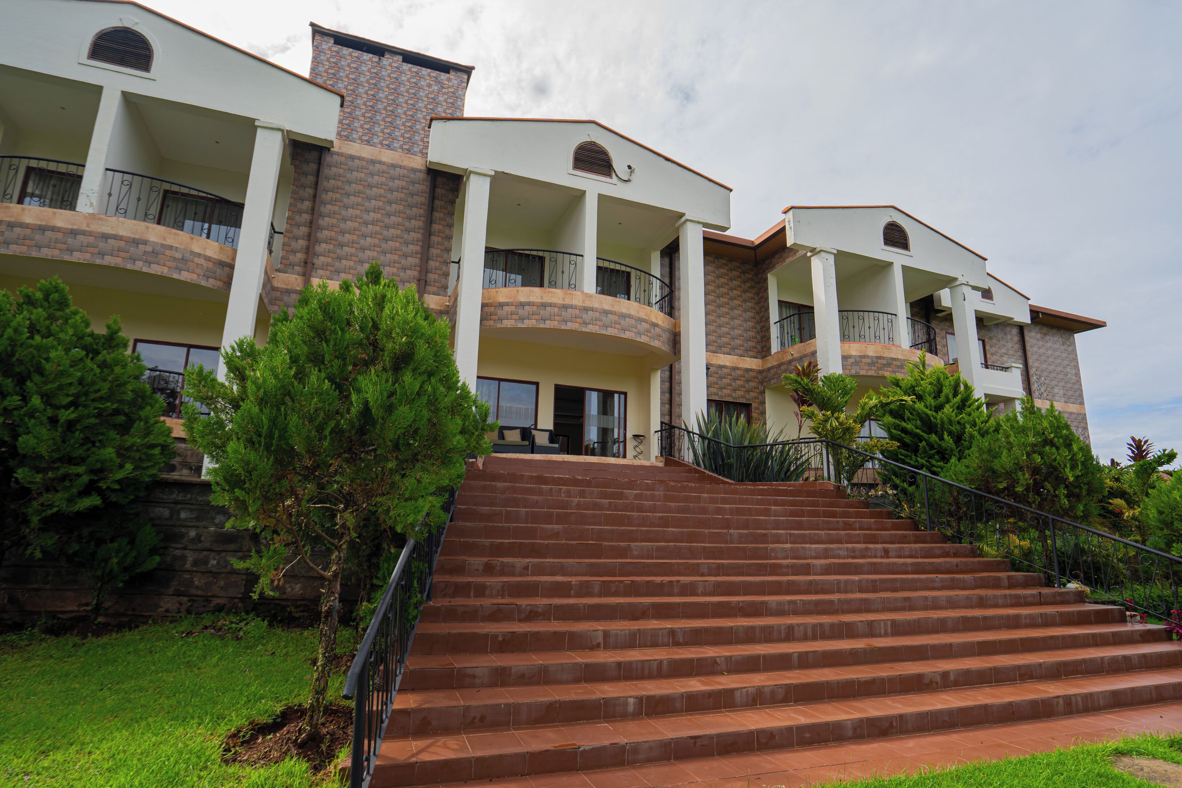 A multi-story hotel with a brick facade, multiple balconies, and a staircase leading to the entrance.