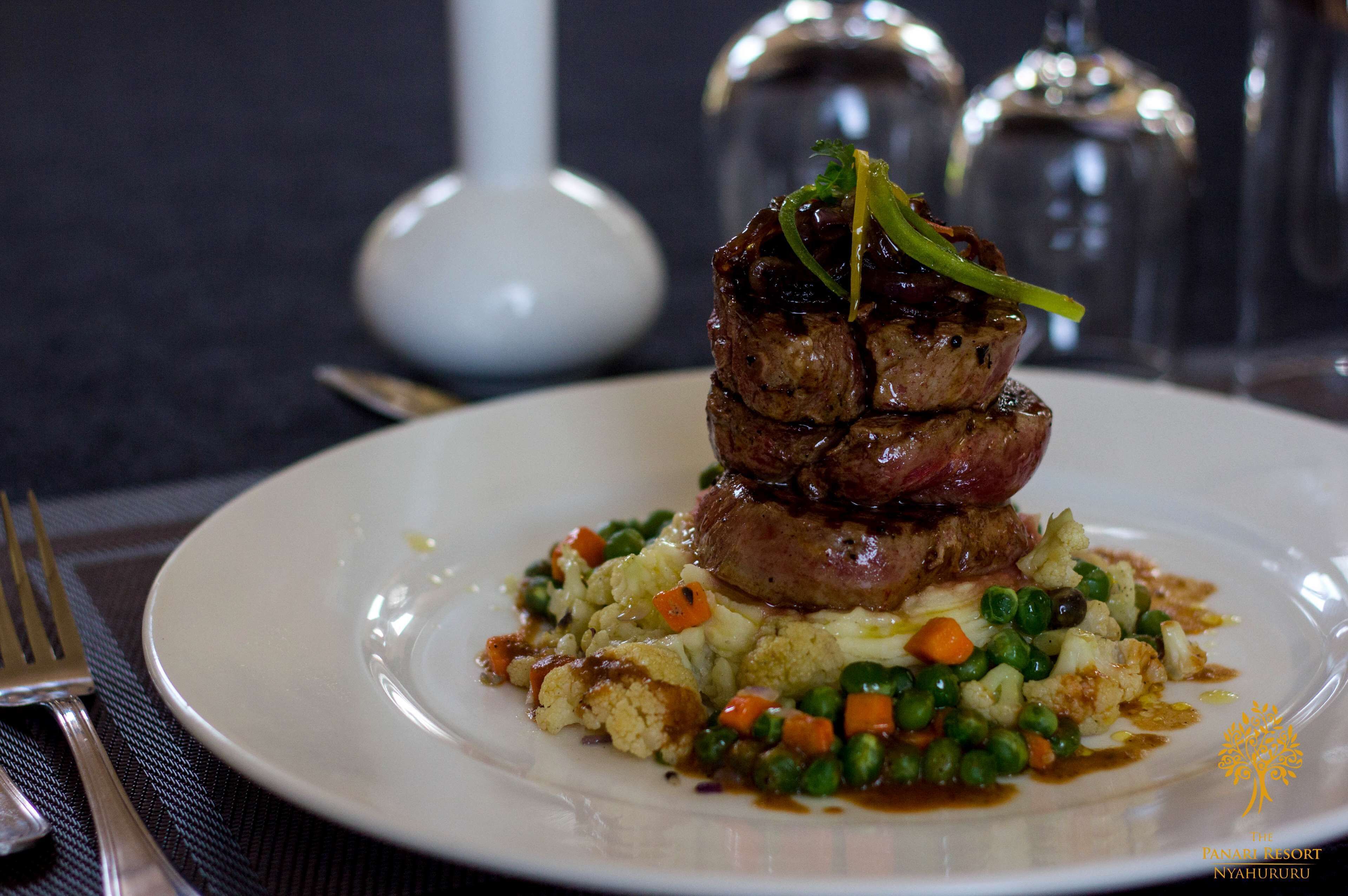 A plate of food with a stack of meat, mashed potatoes, and mixed vegetables.
