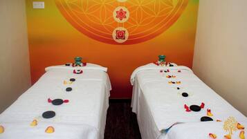 Two plush beds, adorned with decorative stones and flower petals, sit beneath a vibrant, circular wall design.