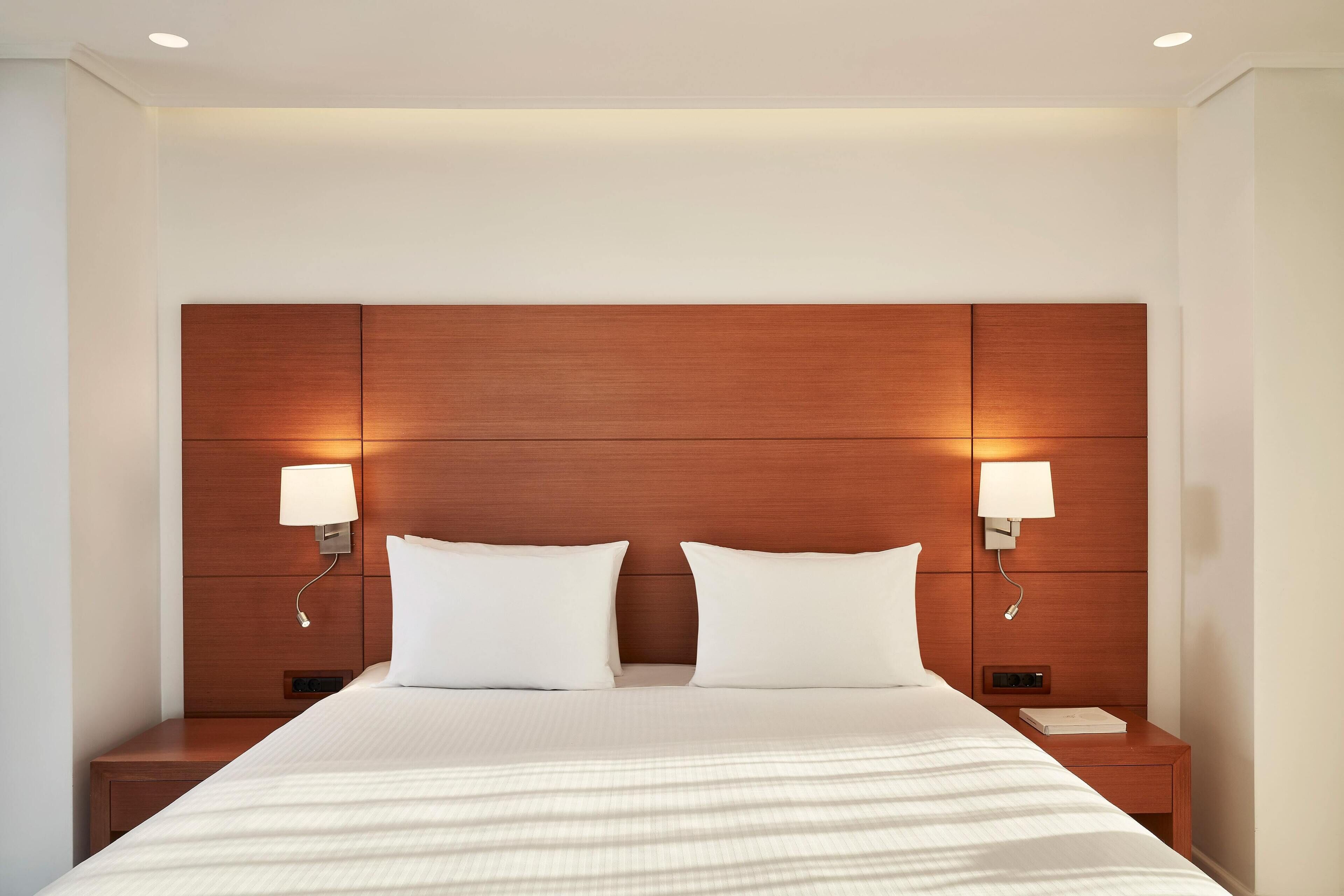 A hotel room with a large bed, two bedside tables, and a wooden headboard.