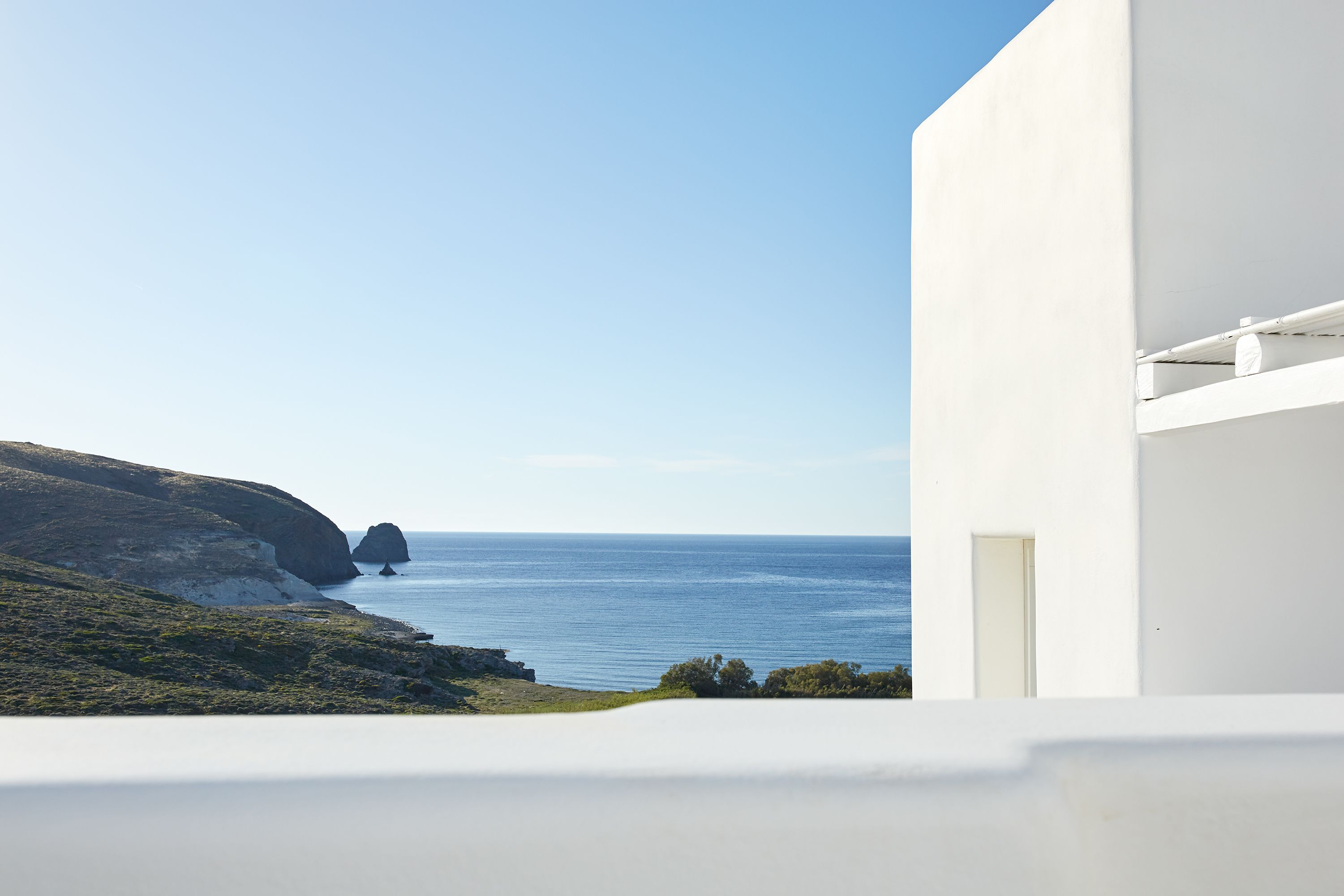 A coastal view with a white building and a rocky landscape.