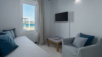 Une chambre avec un lit, une petite table, un téléviseur et une vue sur la mer.