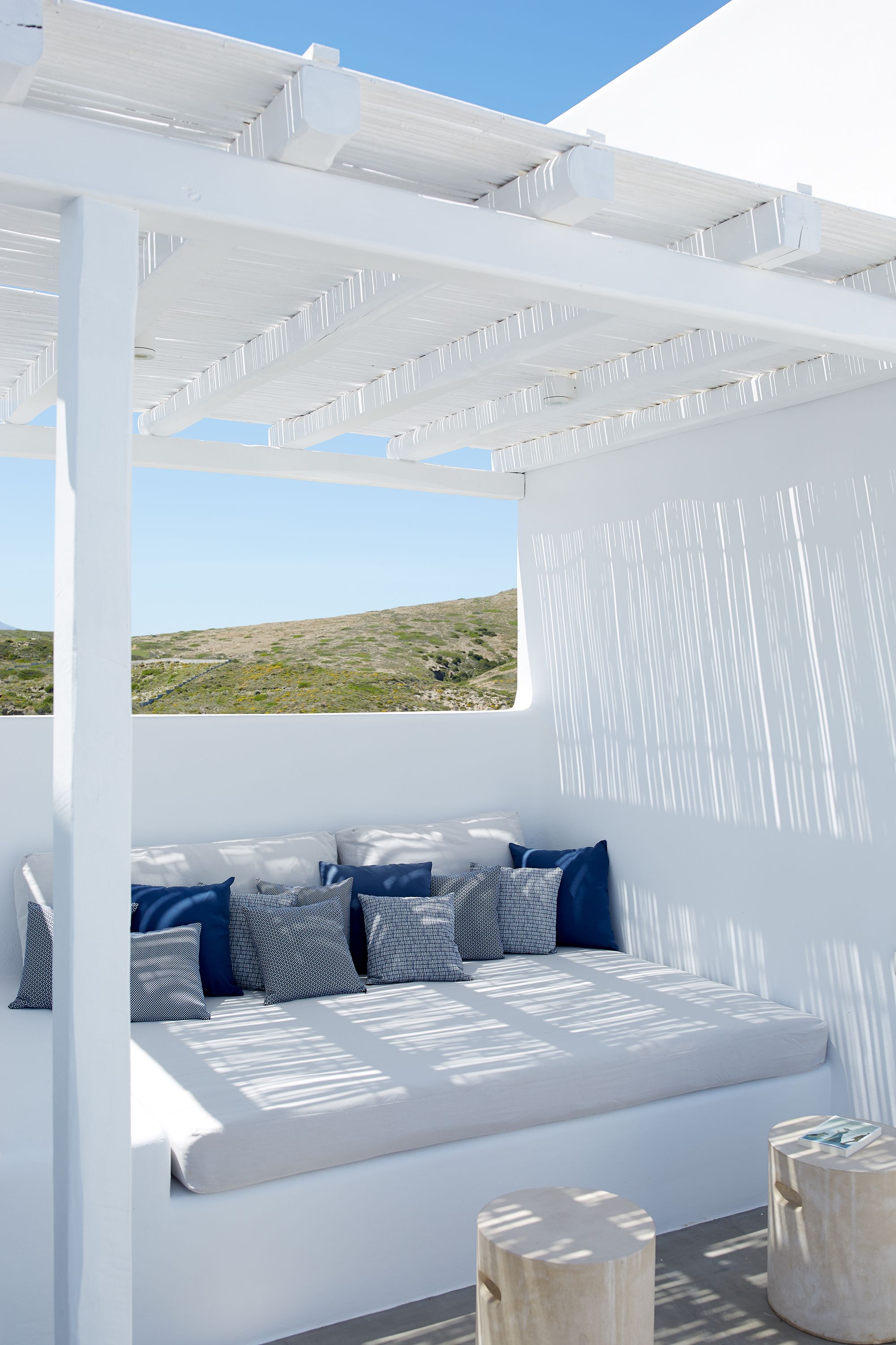 A white outdoor seating area with a view of a hilly landscape.