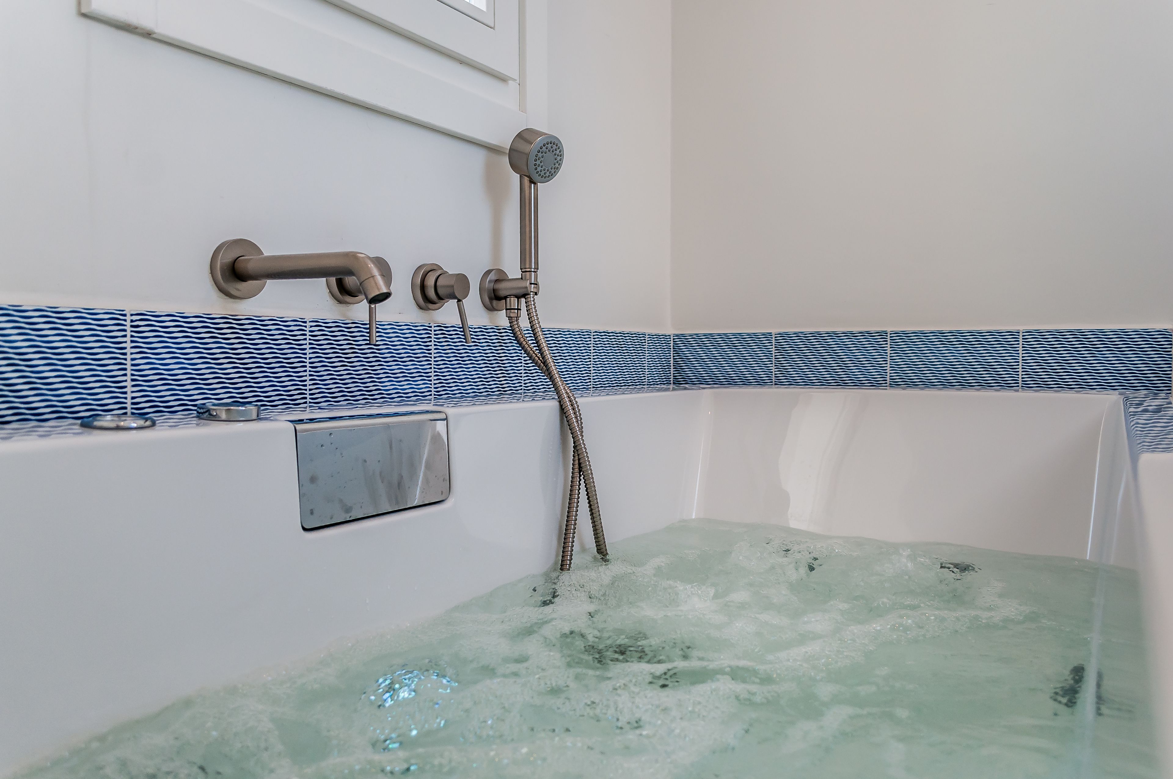 A bathtub with running water, a showerhead, and a towel rack.
