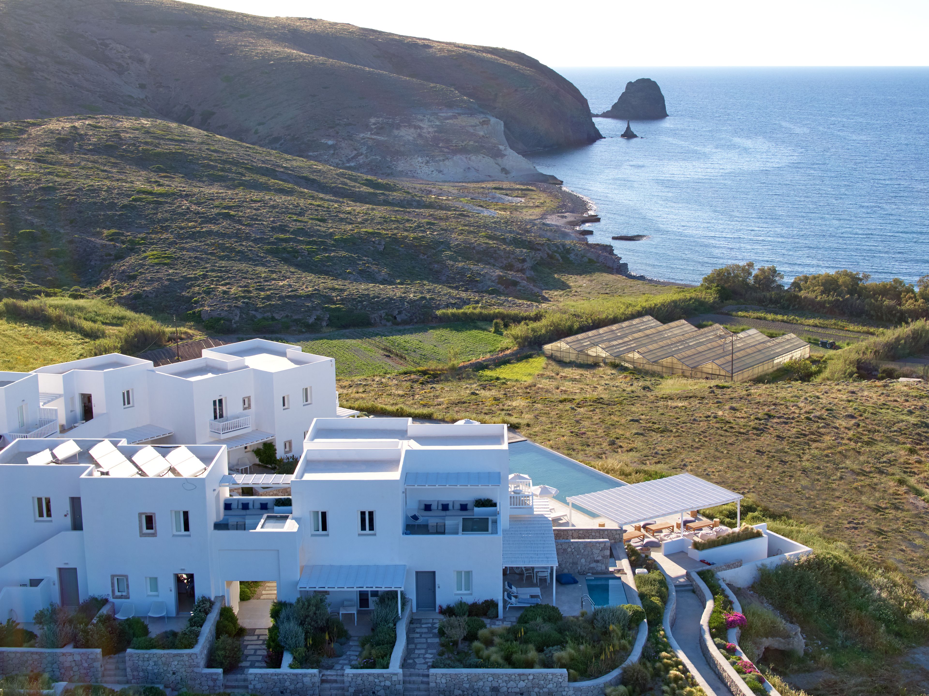 Un bâtiment moderne de couleur blanche, à plusieurs étages, doté d’une piscine et offrant une vue sur la mer et les falaises.