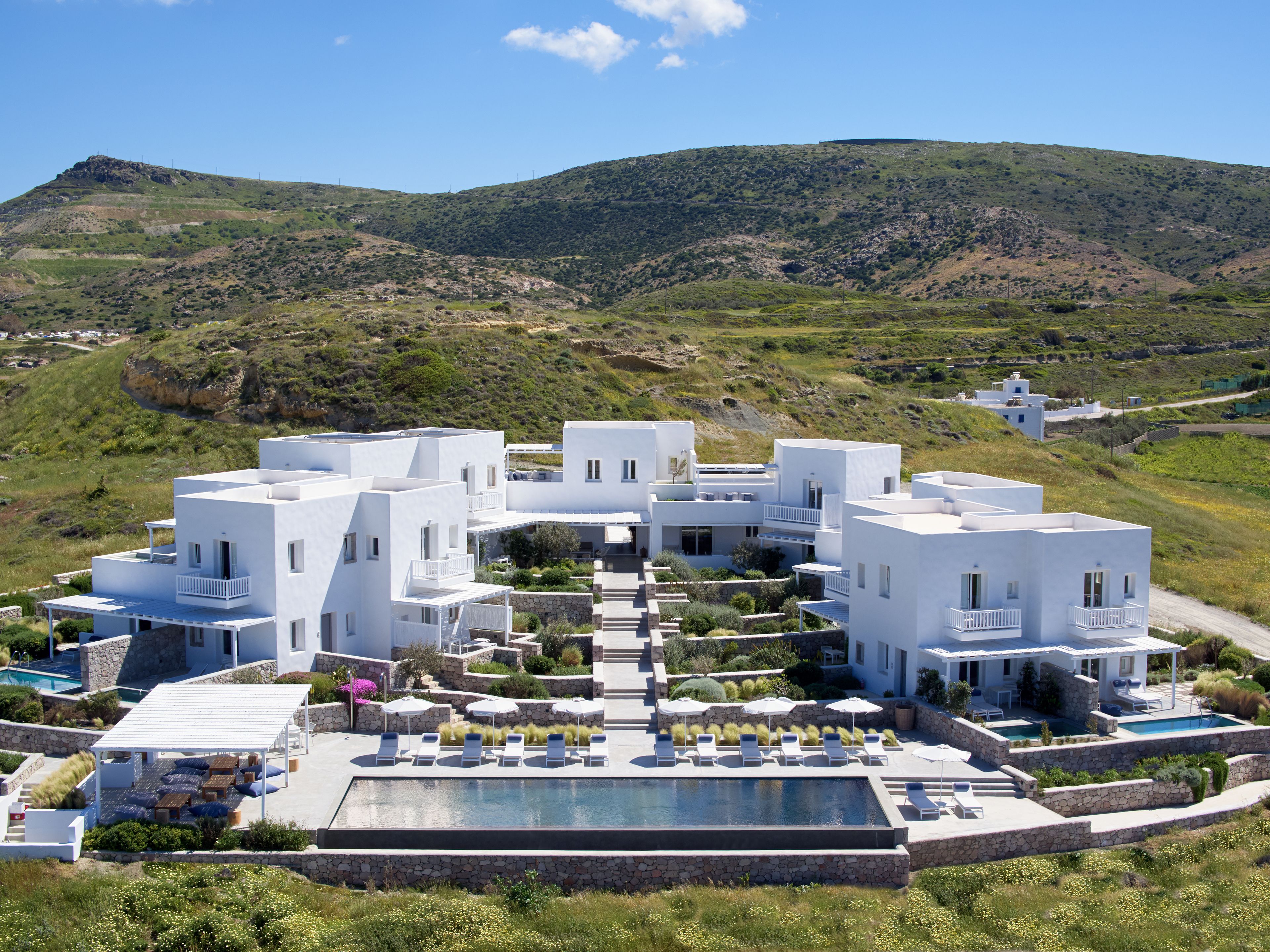 Un bâtiment moderne de couleur blanche, doté d’une piscine et d’un espace extérieur aménagé pour se détendre.