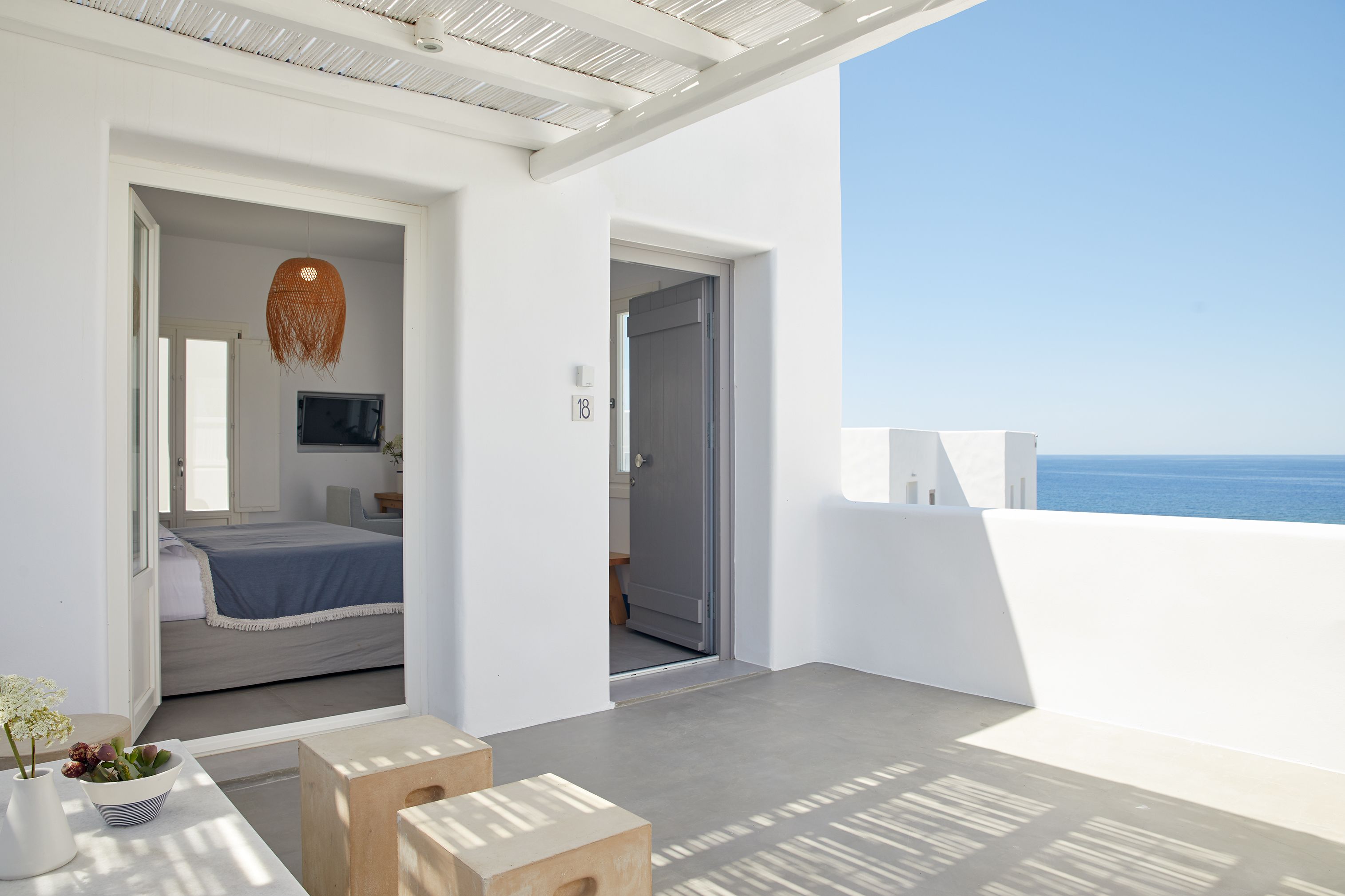 Un dormitorio moderno con cama, televisor y vista al mar.