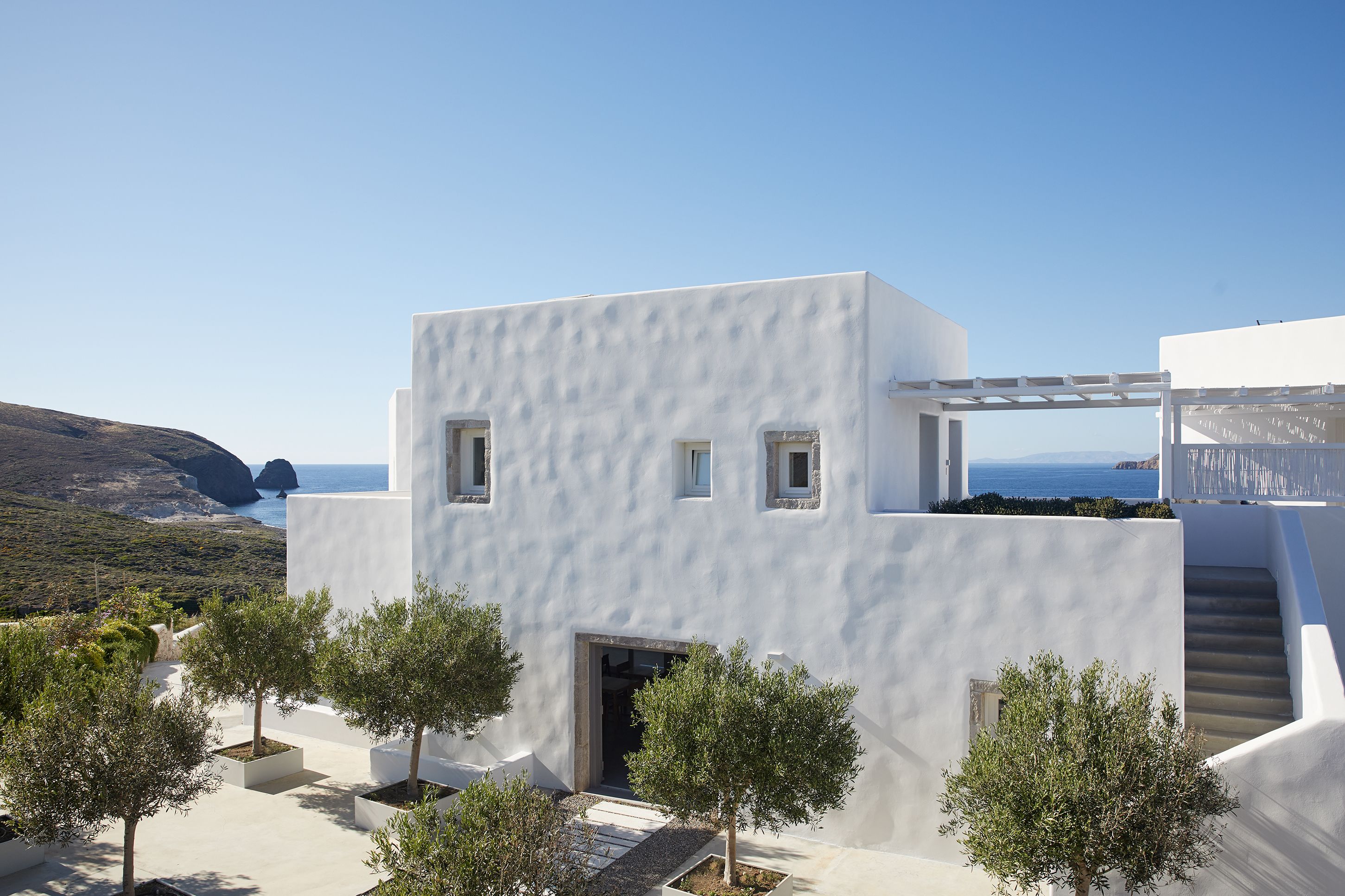 A modern white building with a staircase and a view of the sea.