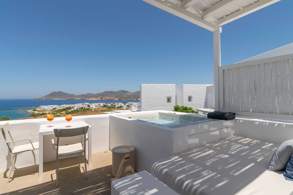 Een terras met een witte bank, een bijzettafeltje en een jacuzzi.