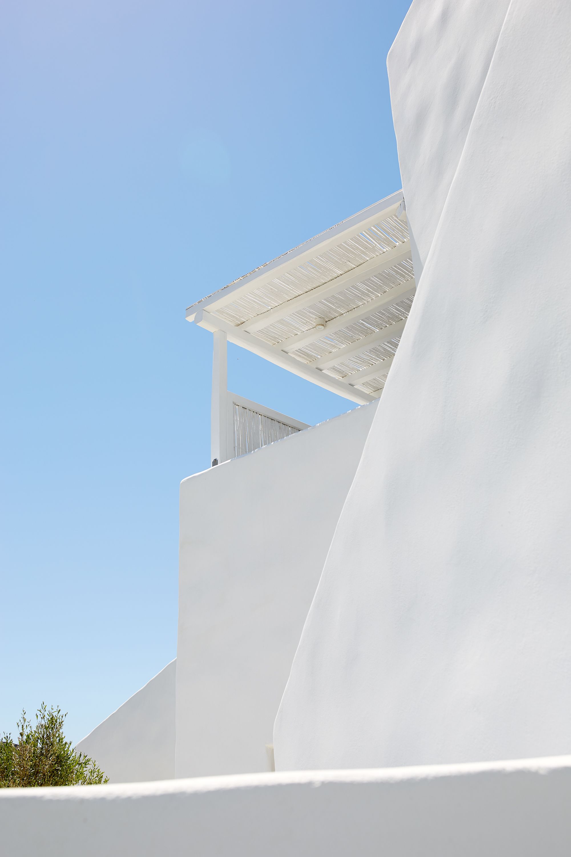 A white building with a sloped roof and a clear blue sky.