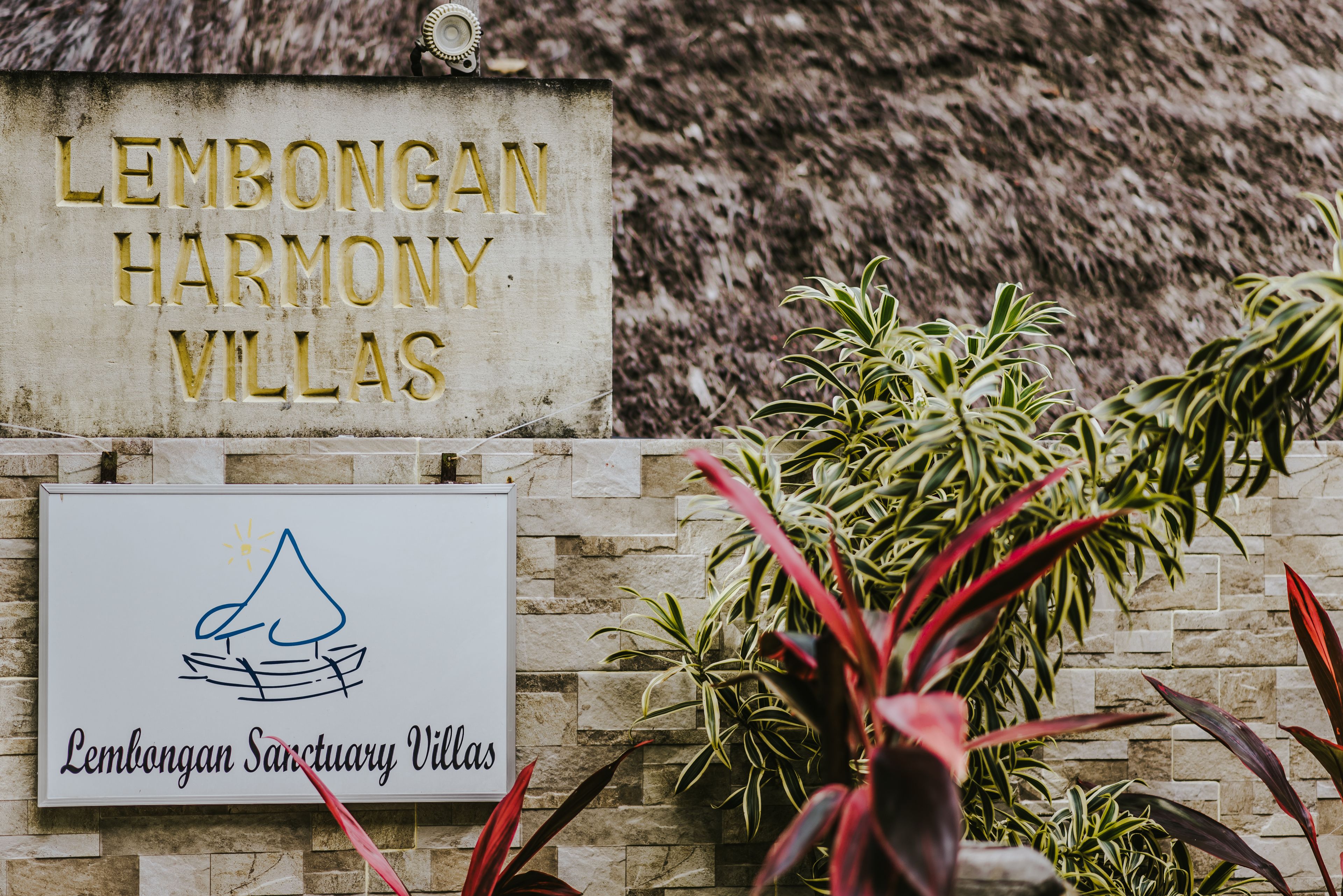A sign for Lembongan Harmony Villas with a logo of a mountain and a boat.