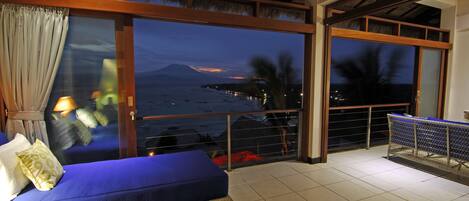 A balcony with a view of the sea and a mountain at dusk.