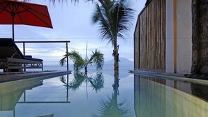 A pool with clear water reflecting palm trees and a mountain in the background. - Lembongan Sanctuary Villas (Lembongan Island)