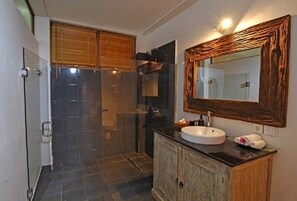 Un baño con cabina de ducha de vidrio, un mueble de madera, un lavabo con espejo y una toalla en la encimera.