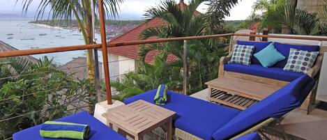 A balcony with blue cushioned seating, a wooden table, and a red umbrella.
