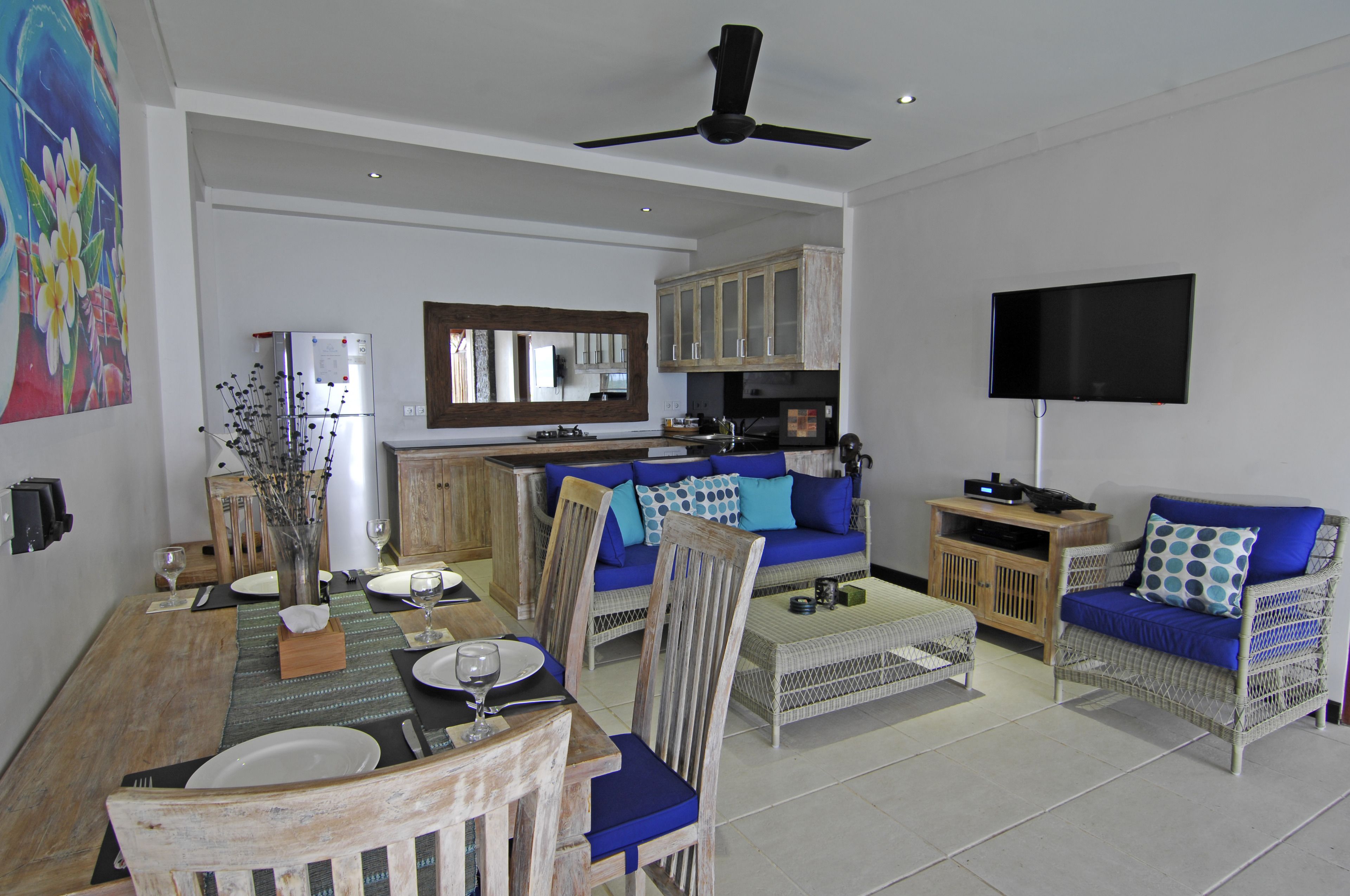 A spacious living area with a dining table, chairs, a sofa, and a television.