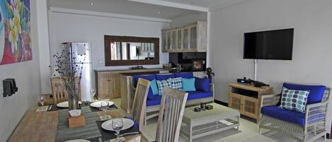A spacious living area with a dining table, chairs, a sofa, and a television.