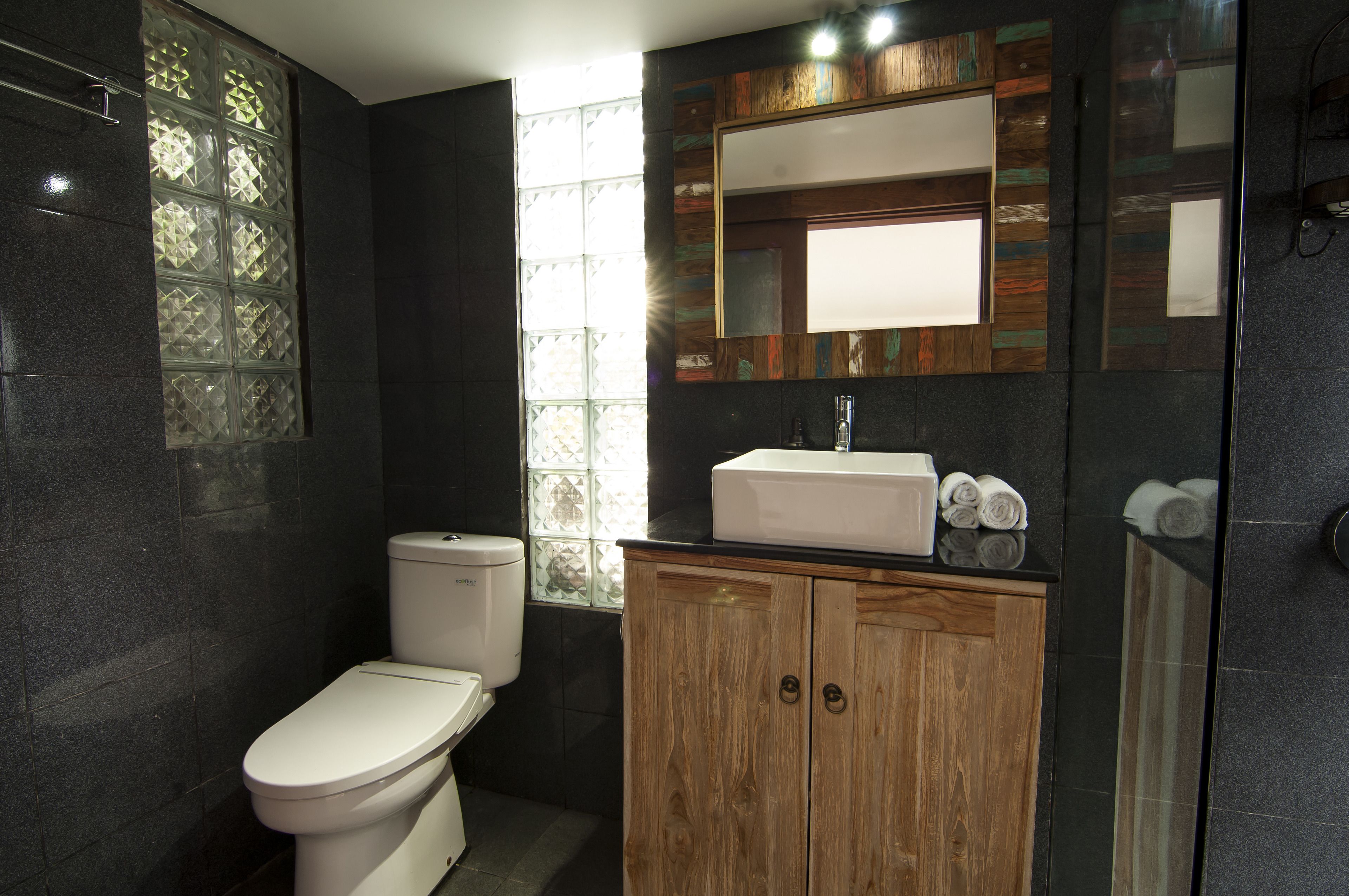 Un baño moderno con inodoro, tocador y un espejo grande.