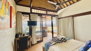 Un dormitorio con cama, escritorio, televisor y vista al exterior.
