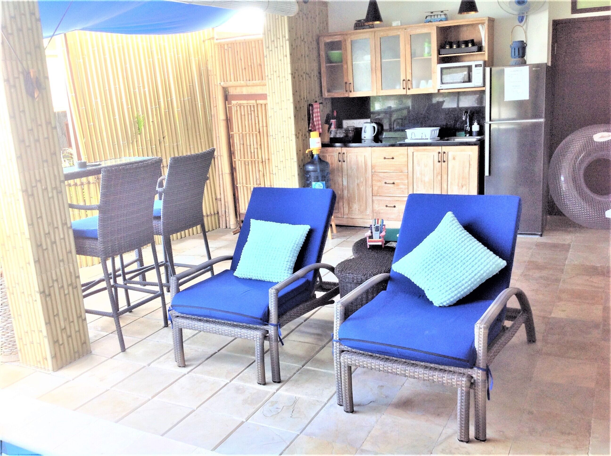 Un espace patio avec des fauteuils de jardin en osier et une cuisine en arrière-plan.
