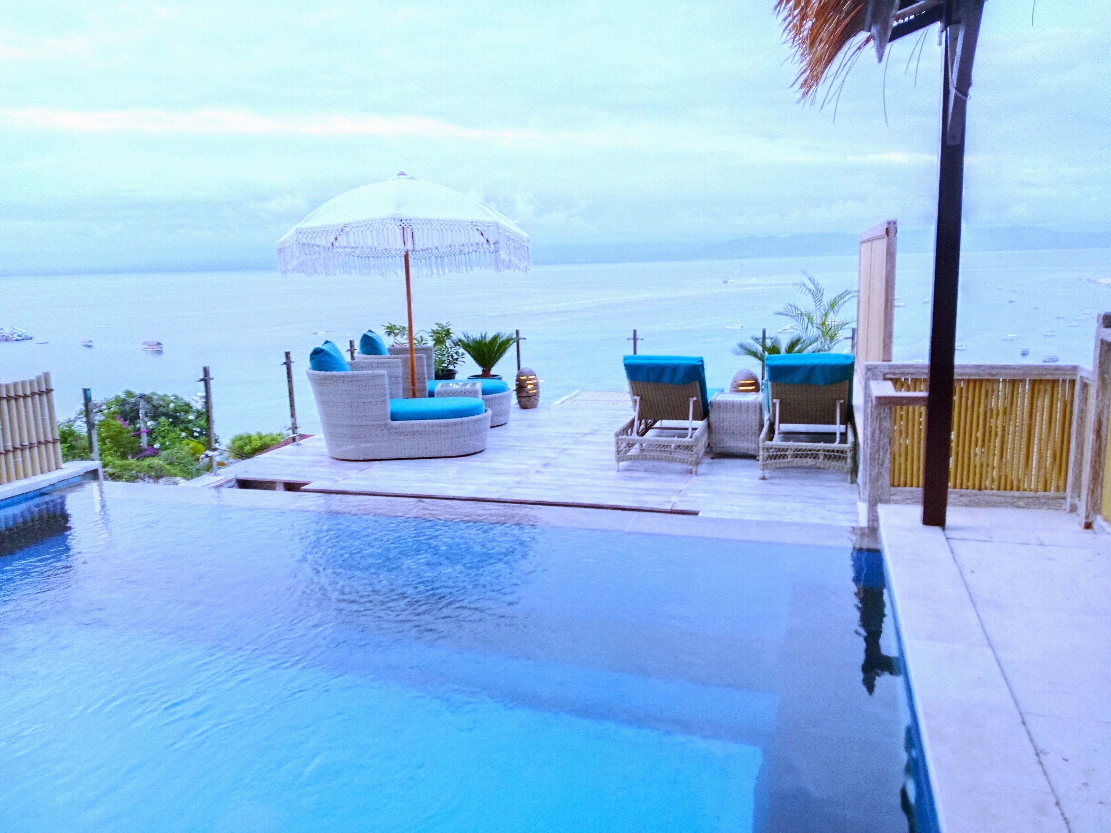 A poolside area with lounge chairs and a canopy, overlooking a body of water.