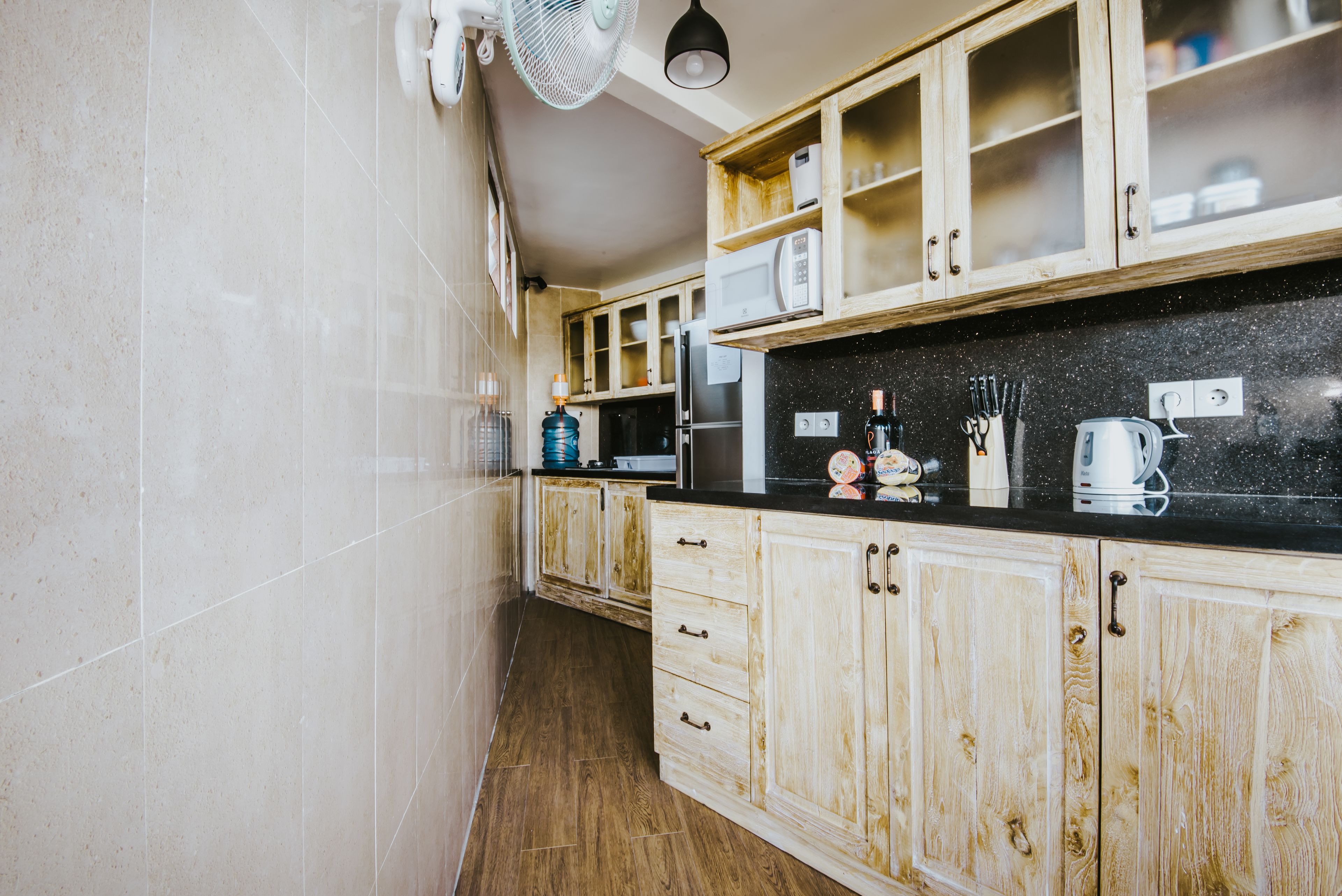 A kitchen with wooden cabinets, a black countertop, and a microwave.