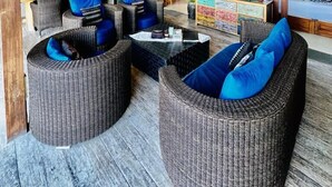 Un salón amplio con mobiliario de mimbre, ventilador de techo y televisor.