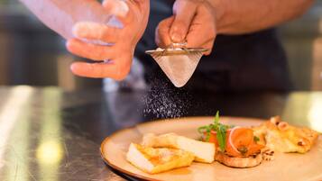 A person sprinkling salt over a dish of food.