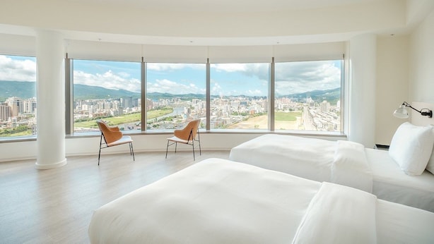 A hotel room with two beds, a large window with a city view, and two chairs. - amba Taipei SongShan (Taipei)