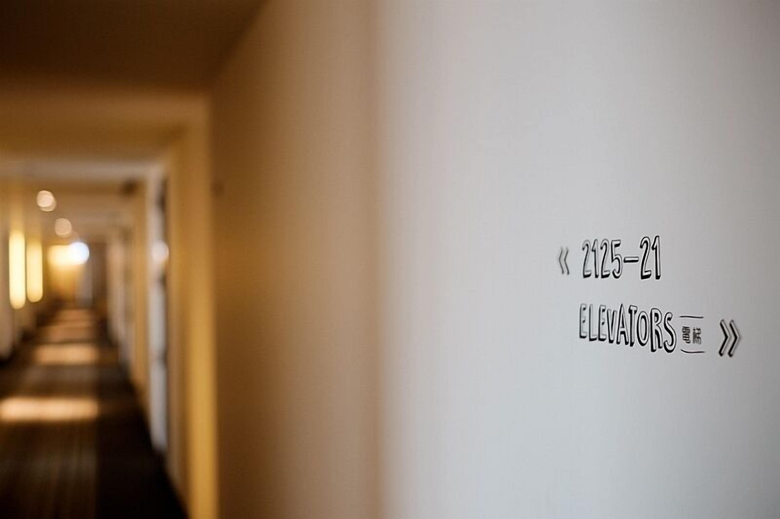 A hallway with a sign indicating the location of elevators.