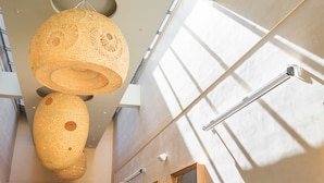 A modern interior with a high ceiling, two large woven light fixtures, and a visible handrail. - amba Taipei SongShan (Taipei)
