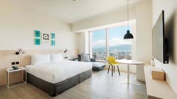 Una habitación de hotel moderna con una cama grande, un escritorio, una silla y un televisor.