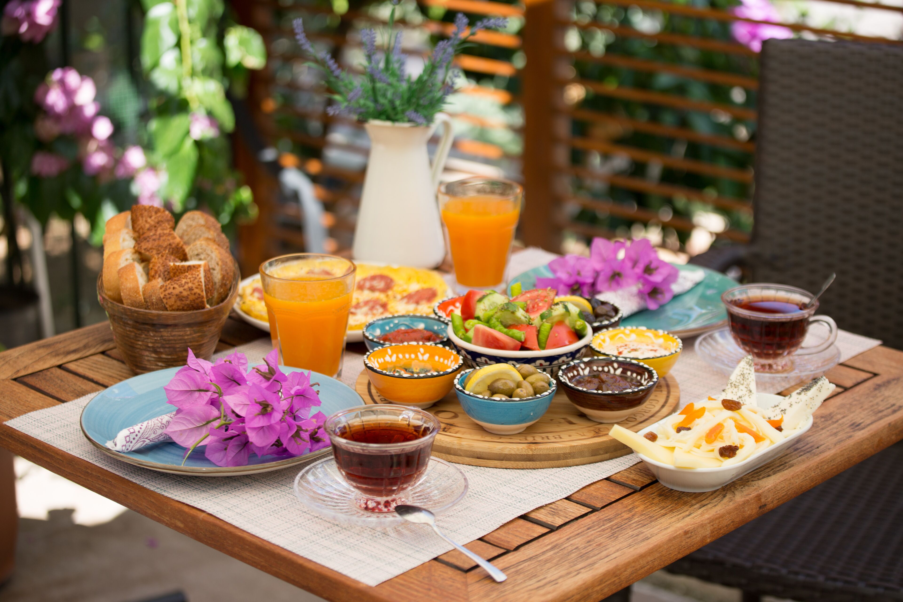 A wooden table with a breakfast spread including bread, fruit, and beverages.