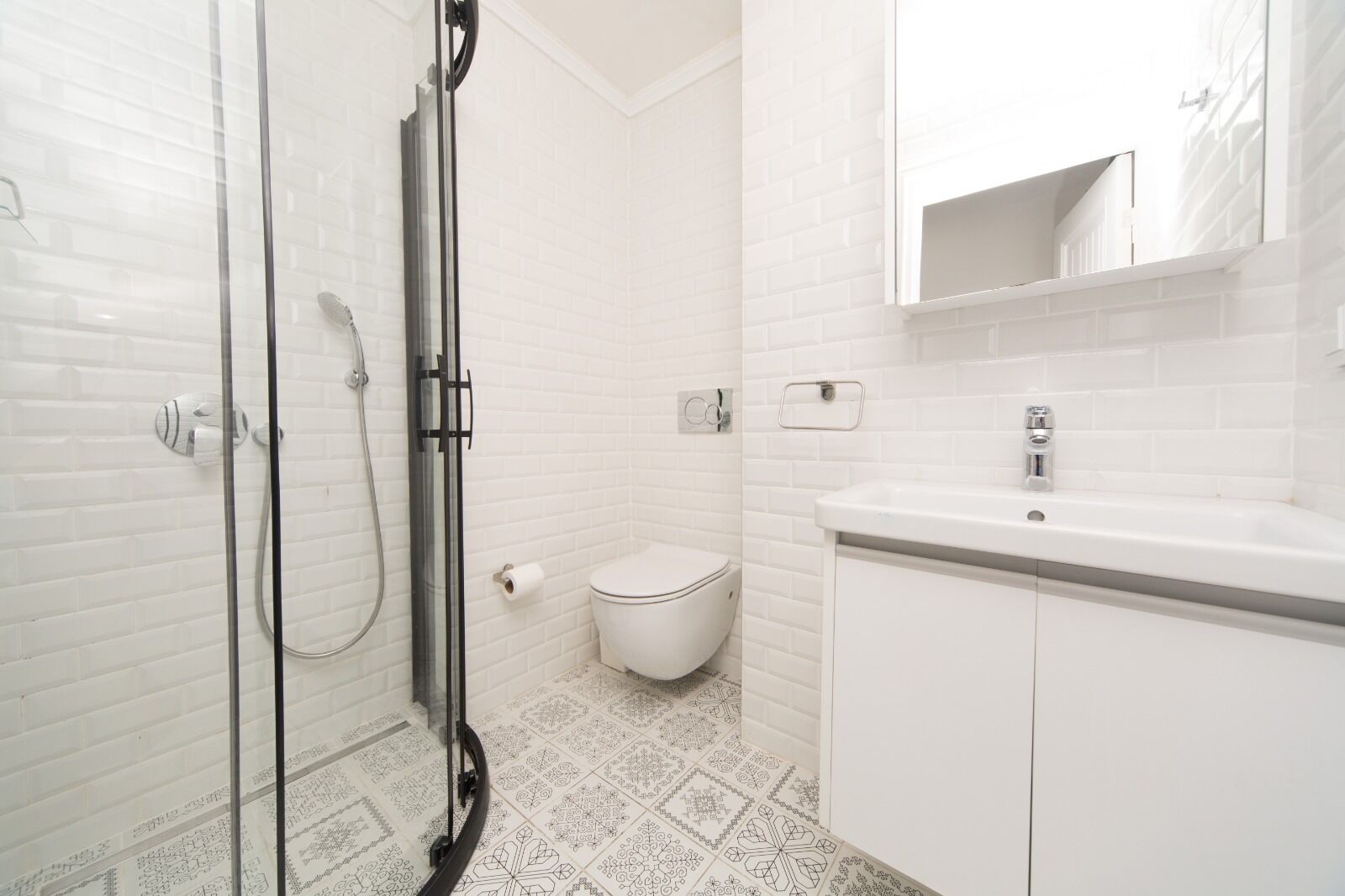 A modern bathroom with a glass shower enclosure, a white toilet, and a sink with a mirror above.