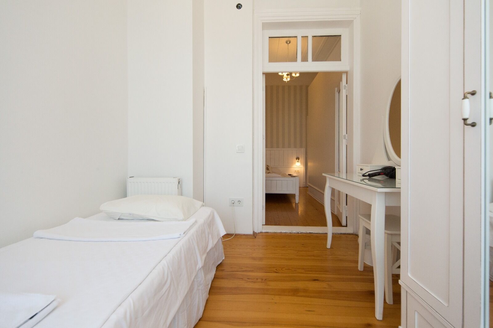 Un dormitorio pequeño y limpio con una cama individual, una mesita de noche y un espejo.
