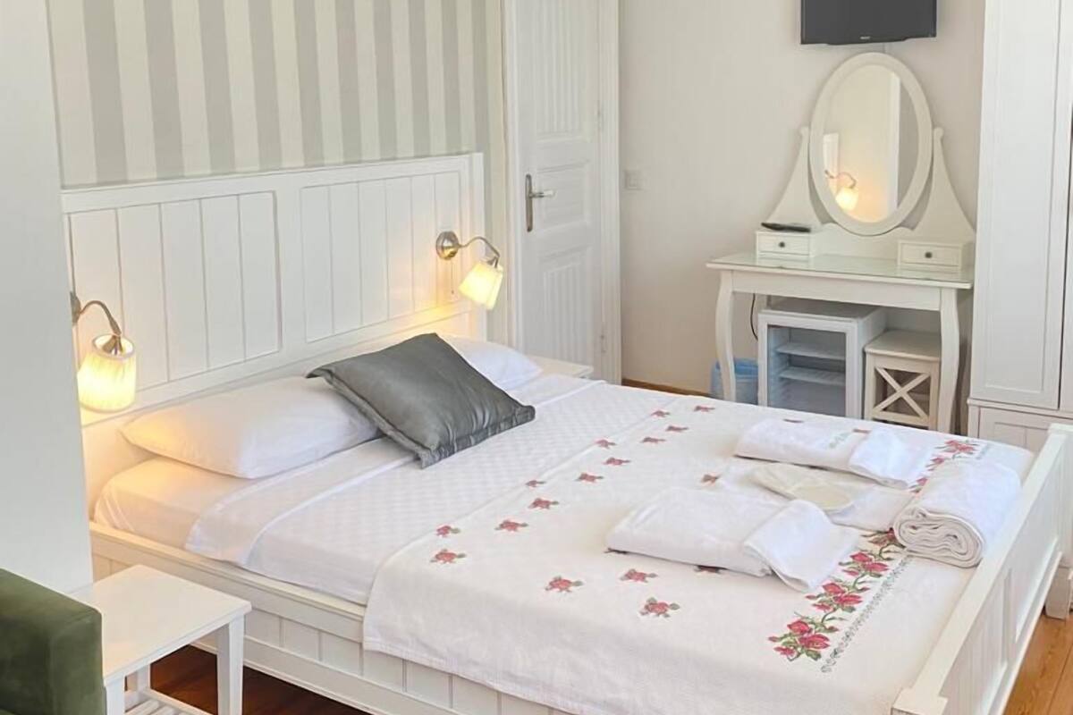 Un dormitorio con cama, mesitas de noche, un espejo, televisión y armario.