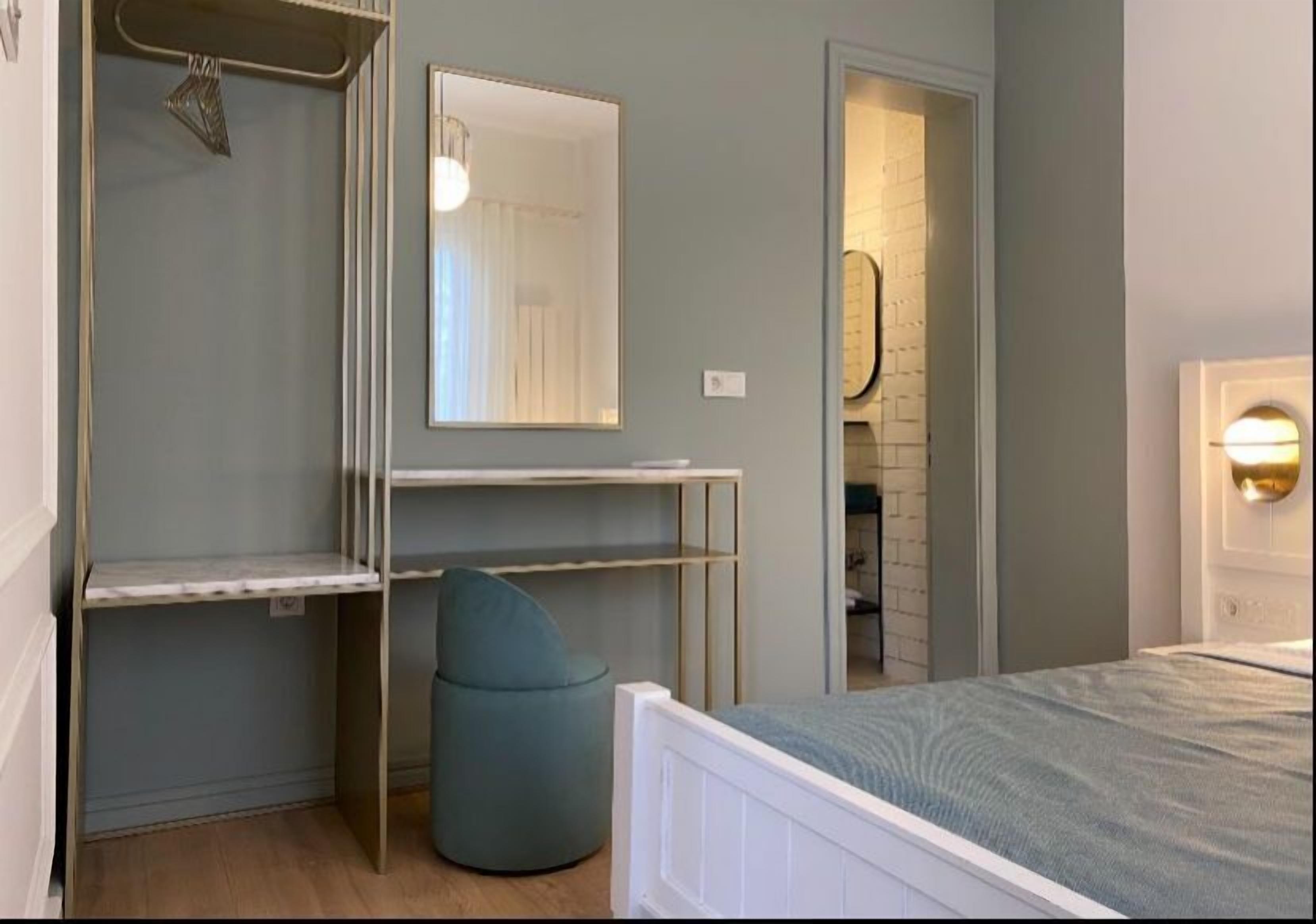 A bedroom with a bed, a wardrobe, a mirror, and a small round seating area.