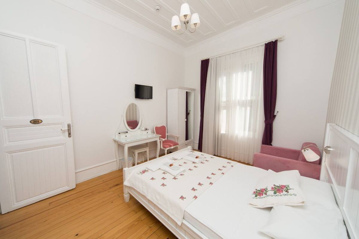 Un dormitorio con cama, tocador con espejo, silla y armario.