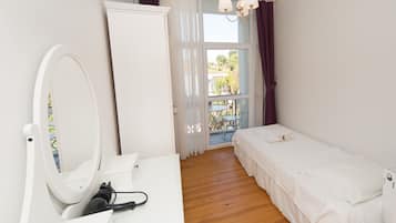 A bedroom with a bed, a dresser, a mirror, and a window with curtains.