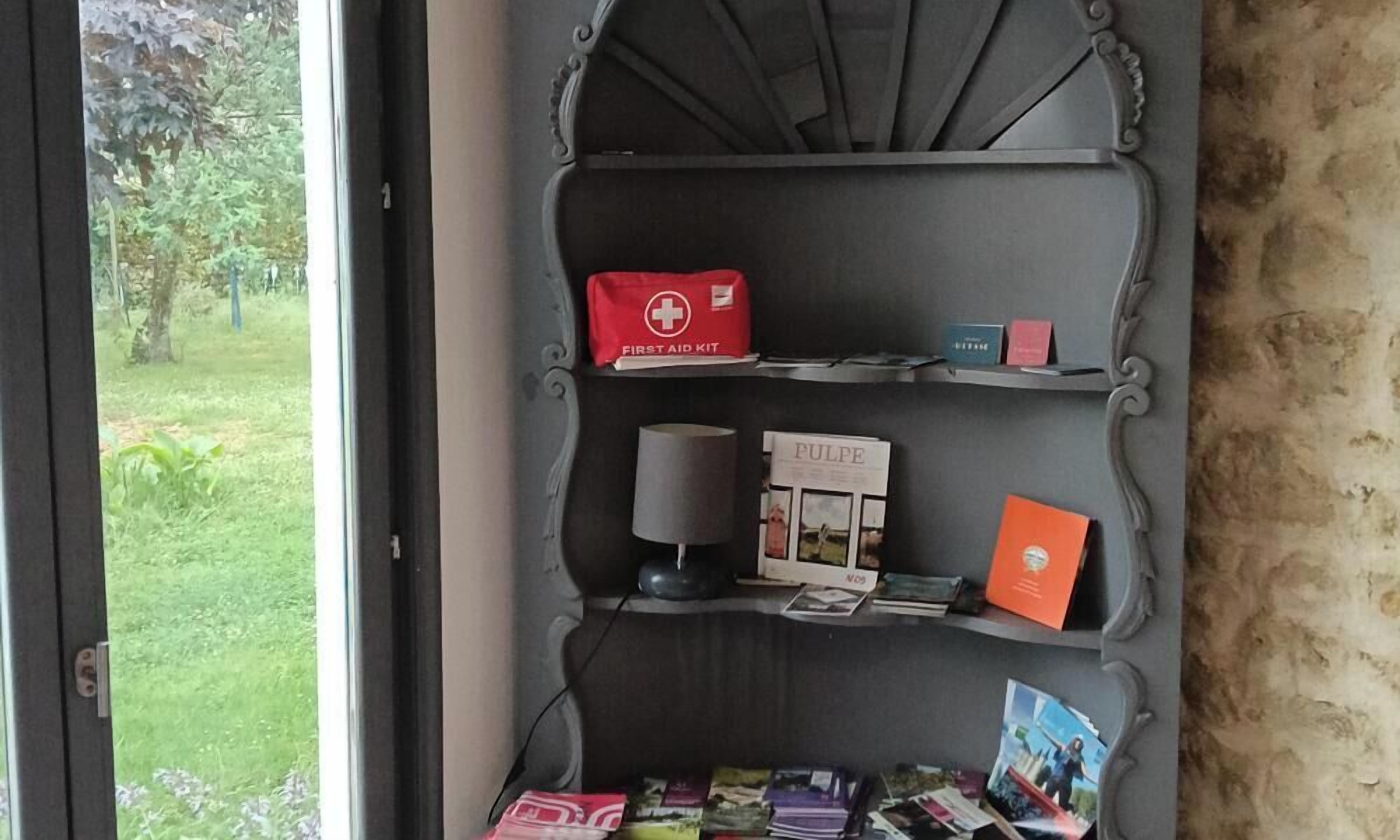 Een plank met een verbanddoos, een doos met de tekst 'PULPE' en enkele boeken.