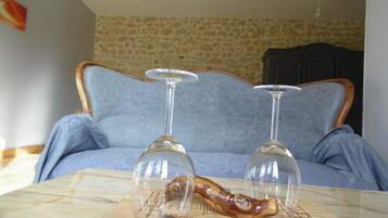 A room with a stone wall, a blue sofa, and two wine glasses on a wooden coaster.