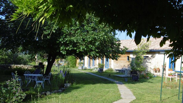 A garden with a wooden pathway leading to a building with blue shutters. - La Cadournaise (Saint-Seurin-de-Cadourne)