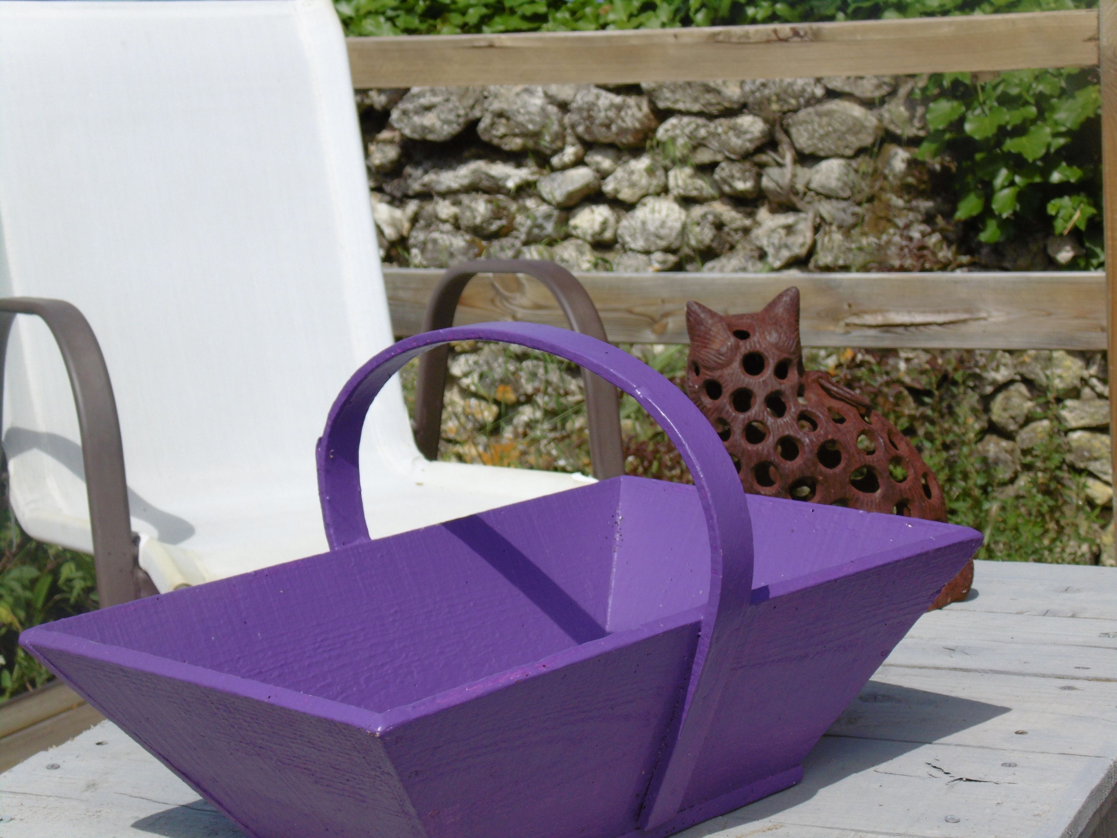Una cesta púrpura con asas sobre una mesa de madera.
