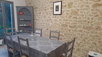 Un comedor con pared de piedra, un certificado enmarcado en la pared y un botiquín en un estante.